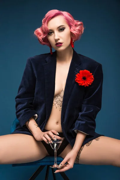 Sexy tatoué pin up fille en veste avec boutonnière et verre à vin infront de fond bleu — Photo de stock