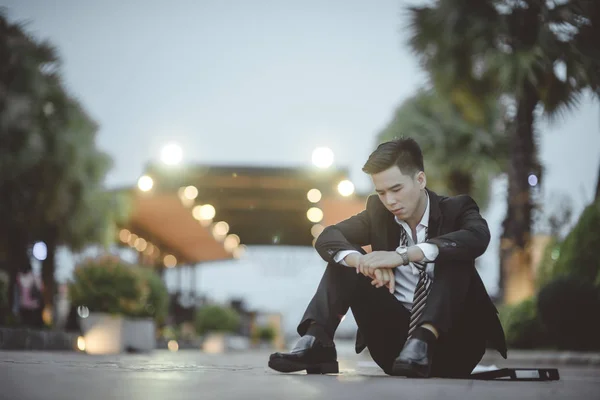 Tired or stressed businessman sitting on the walkway in the city