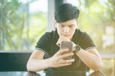 Evinde kanepede otururken Smartphone kullanarak çekici iş adamı. Mobil cihazlar çalışan genç insanlar kavramı. Seçili bir odak portre. Arka plan bulanık. 