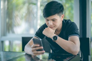 Evinde kanepede otururken Smartphone kullanarak çekici iş adamı. Mobil cihazlar çalışan genç insanlar kavramı. Seçili bir odak portre. Arka plan bulanık. 