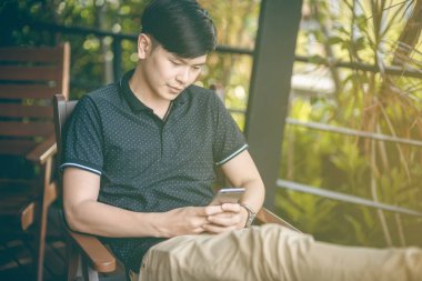 Evinde kanepede otururken Smartphone kullanarak çekici iş adamı. Mobil cihazlar çalışan genç insanlar kavramı. Seçili bir odak portre. Arka plan bulanık. 