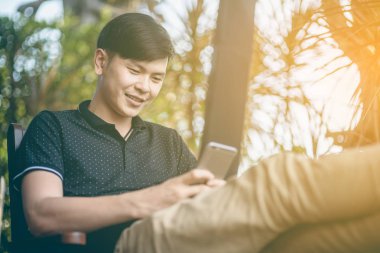 Evinde kanepede otururken Smartphone kullanarak çekici iş adamı. Mobil cihazlar çalışan genç insanlar kavramı. Seçili bir odak portre. Arka plan bulanık. 