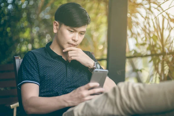 Evinde kanepede otururken Smartphone kullanarak çekici iş adamı. Mobil cihazlar çalışan genç insanlar kavramı. Seçili bir odak portre. Arka plan bulanık. 