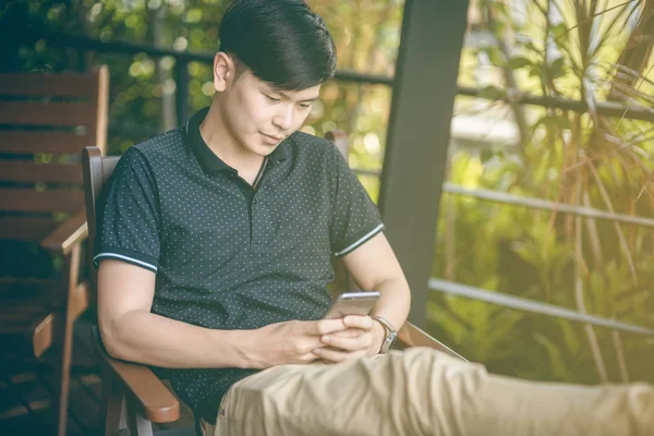 Evinde kanepede otururken Smartphone kullanarak çekici iş adamı. Mobil cihazlar çalışan genç insanlar kavramı. Seçili bir odak portre. Arka plan bulanık. 