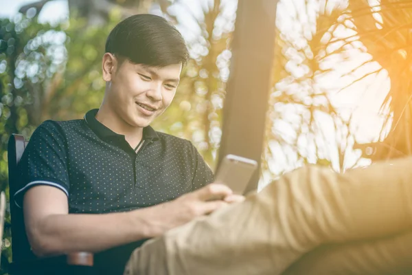 Evinde kanepede otururken Smartphone kullanarak çekici iş adamı. Mobil cihazlar çalışan genç insanlar kavramı. Seçili bir odak portre. Arka plan bulanık. 