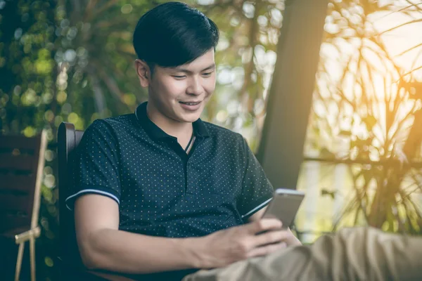 Evinde kanepede otururken Smartphone kullanarak çekici iş adamı. Mobil cihazlar çalışan genç insanlar kavramı. Seçili bir odak portre. Arka plan bulanık. 