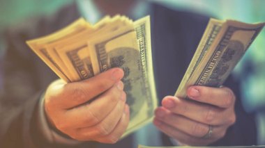 Bir adam elinde, para para biri bizi Doları banknot ve holding nakit elinde veren adam onun elinde tutan işadamı dolar tutar. Para kredi kavramı. Dikey görüntü. Seçici odak