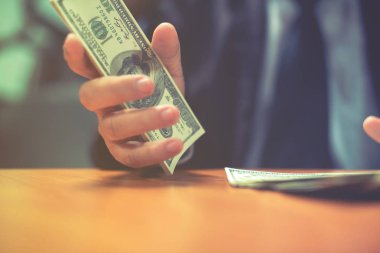 Bir adam elinde, para para biri bizi Doları banknot ve holding nakit elinde veren adam onun elinde tutan işadamı dolar tutar. Para kredi kavramı. Dikey görüntü. Seçici odak
