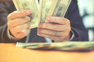 Bir adam elinde, para para biri bizi Doları banknot ve holding nakit elinde veren adam onun elinde tutan işadamı dolar tutar. Para kredi kavramı. Dikey görüntü. Seçici odak