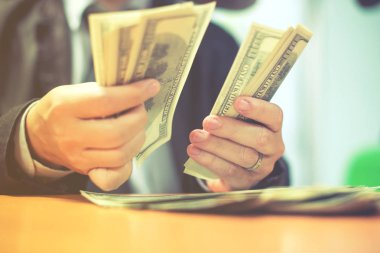 Bir adam elinde, para para biri bizi Doları banknot ve holding nakit elinde veren adam onun elinde tutan işadamı dolar tutar. Para kredi kavramı. Dikey görüntü. Seçici odak