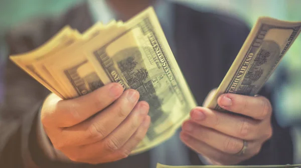 A man holds dollars in his hands, Businessman holding money in his hands, Man giving money one us dollar banknote and holding cash in hands. Money credit concept. Vertical image. Selective focus