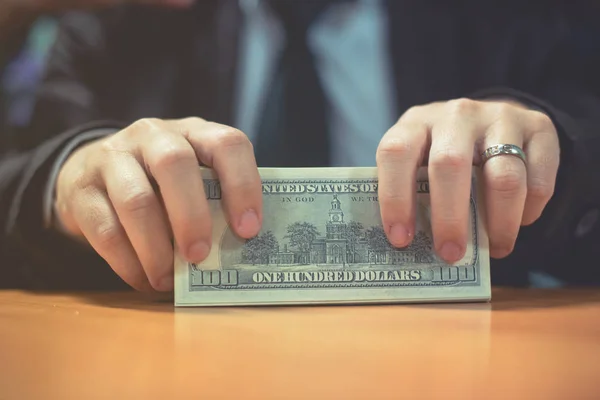 Bir adam elinde, para para biri bizi Doları banknot ve holding nakit elinde veren adam onun elinde tutan işadamı dolar tutar. Para kredi kavramı. Dikey görüntü. Seçici odak