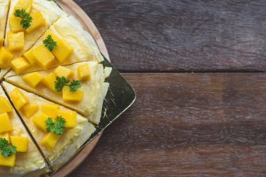 taze mango ile mango krep, kremsi mango mousse kek Beyaz ahşap zemin üzerine kapatın. Tonlama. seçici odak, Mango cheesecake çatal ile beyaz plaka üzerinde