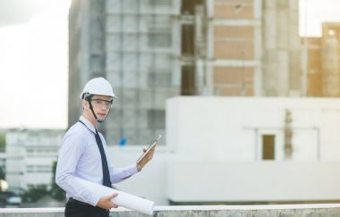 Gülümseyen genç mimar veya Oluşturucusu'nda kask ile mühendislik 