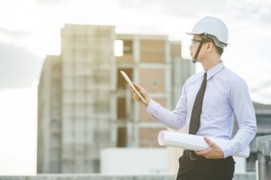 Gülümseyen genç mimar veya Oluşturucusu'nda kask ile mühendislik 