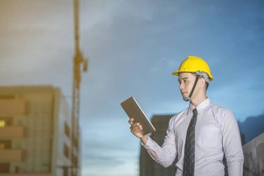 Gülümseyen genç mimar veya Oluşturucusu'nda kask ile mühendislik 