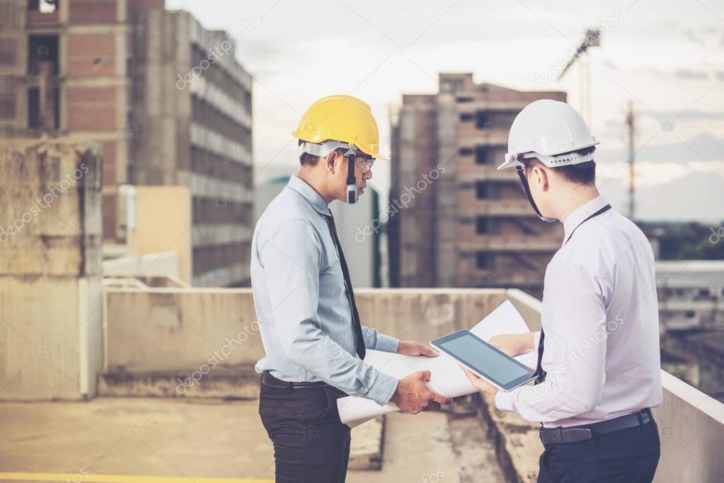 Smiling young architect or engineering builder in hard hat with 