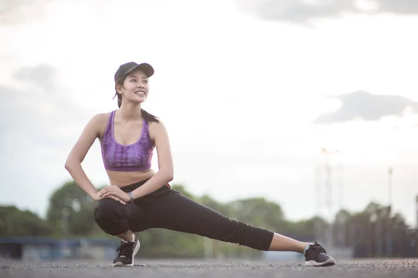 Sonriente de mujer atleta de Asia sentada en una esterilla de ejercicio y str — Foto de Stock