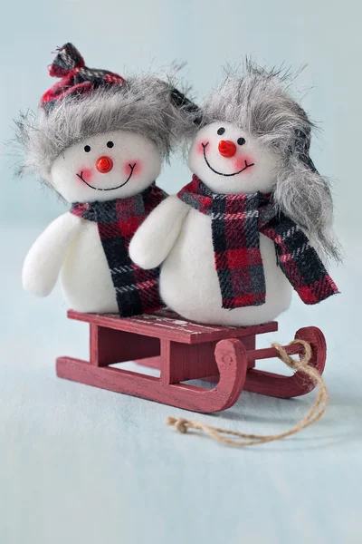Twee grappige sneeuwmannen op een slee . — Stockfoto