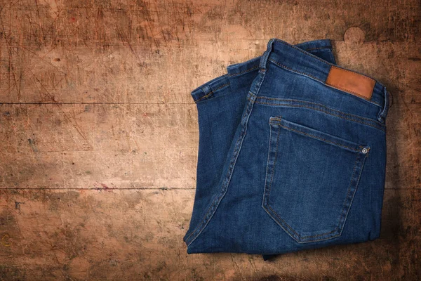 Mavi jeans ahşap arka plan üzerinde katlanmış — Stok fotoğraf