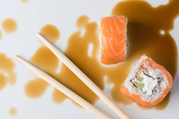 Rouleau de sushi en baguettes en sauce soja, gros plan — Photo