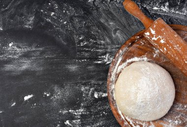 Hamur hazırlığı. Koyu arkaplanda un olan merdane. Metin için boş alan.