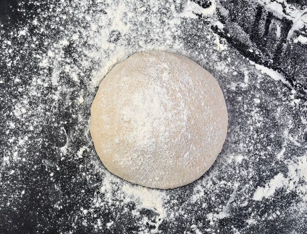 Preparation of the dough. The rolling pin with flour on a dark background.