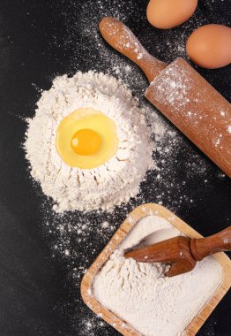 Siyah arka planda yuvarlak iğne ve beyaz un. Üst görünüm.