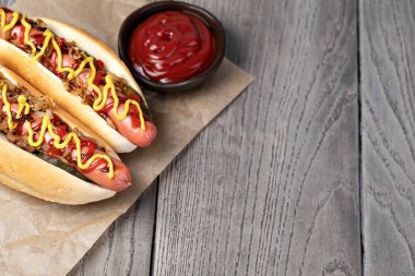 Sarı hardallı ızgara sosisli sandviç ve ahşap masada ketçap.