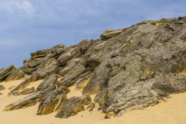 Çok sayıda mağara ve bulutlu gökyüzü altında görünür erozyon ile kırmızı kumtaşı biri üst