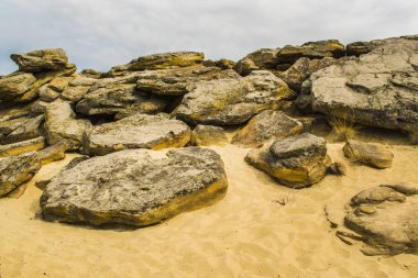 Çok sayıda mağara ve bulutlu gökyüzü altında görünür erozyon ile kırmızı kumtaşı biri tepesine. Sarı kum