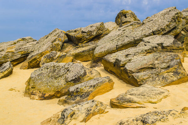 The top of one of the red sandstones with its numerous caves and visible erosion under the cloudy sky