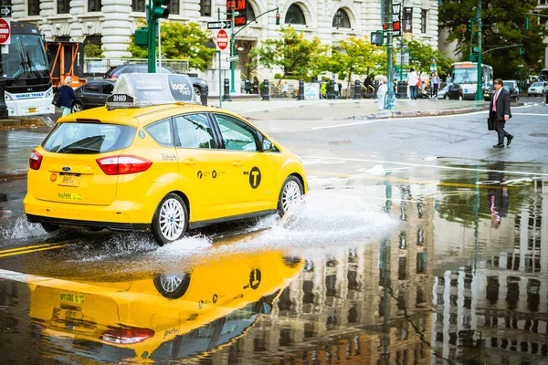 Taxi en camino mojado reflejándose en charco — Foto de Stock