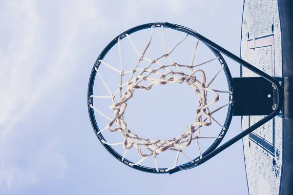 青い金属製のバスケットボールリングを空に対して白いネットで見る — ストック写真
