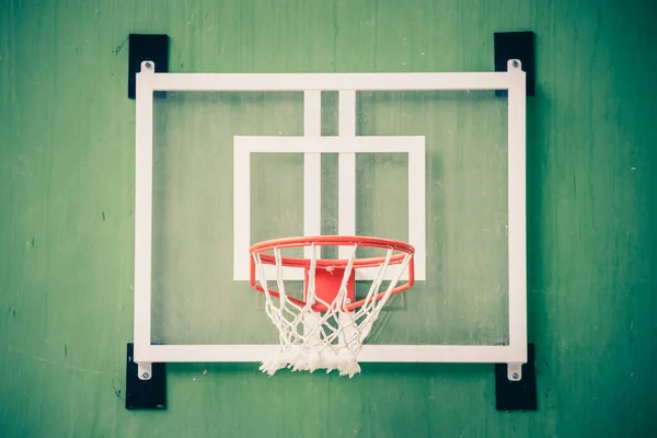 体育館の緑の壁の上のバスケットボールフープの正面図 — ストック写真