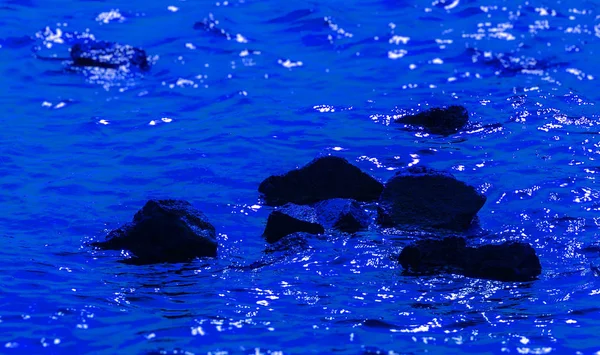 derin mavi su siyah taşlarla