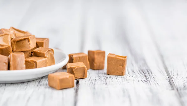 Porção de peças de caramelo no fundo de madeira — Fotografia de Stock