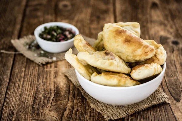 Některé empanadas na starožitném dřevěném stole (selektivní výběr; zavřít — Stock fotografie