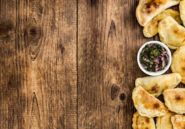 Ξύλινο τραπέζι με empanadas (λεπτομερή κοντινό πλάνο, επιλεκτική f — Φωτογραφία Αρχείου