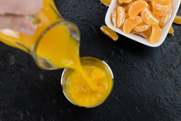 Frisch gepresster Mandarinensaft (auf einer Schieferplatte; selektiver Fokus) — Stockfoto