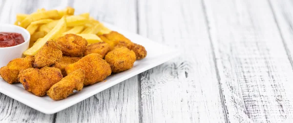 Vintage wooden table with fresh made Chicken Nuggets (close-up shot; selective focus)