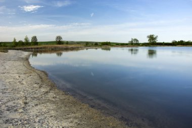 Göl, ufuk ve mavi gökyüzü sahilde kum