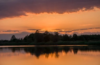 Gün batımından sonra renkli bulutlar, göl kıyısında