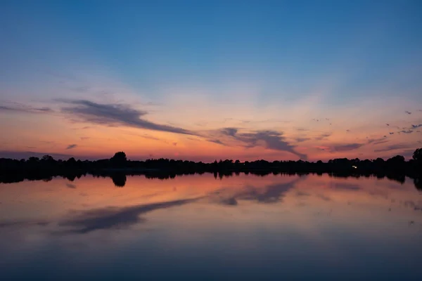 Nubes coloridas después de la puesta del sol, reflejo del espejo en el lago — Foto de Stock