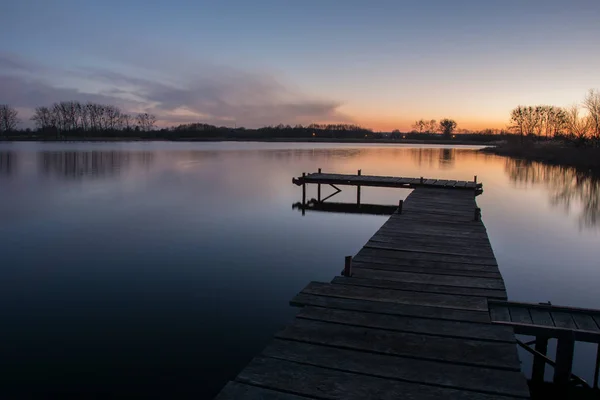Longo molhe no lago e um céu colorido após o pôr do sol — Fotografia de Stock