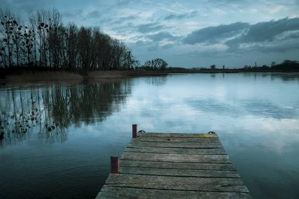 Bewölkt und kalt Winterabend, zugefrorener See mit Seebrücke — Stockfoto