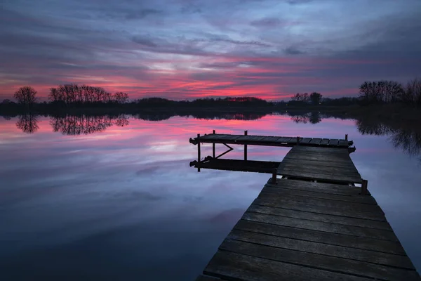 Rosafarbener Sonnenuntergang mit dramatischen Wolken, See und Holzsteg — Stockfoto