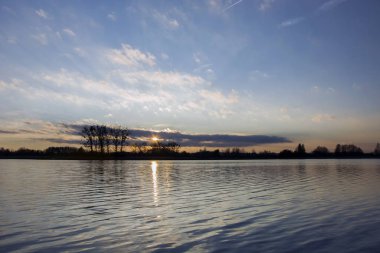 Suyun üzerinde gün batımı ve mavi gökyüzü, güzellik manzarası