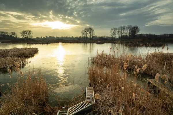 Uma Ponte Entre Juncos Margem Lago Congelado Pôr Sol Atrás — Fotografia de Stock