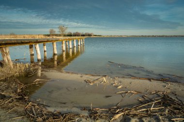 Kumsal ve ahşap iskele, akşam bulutları mavi gökyüzünde